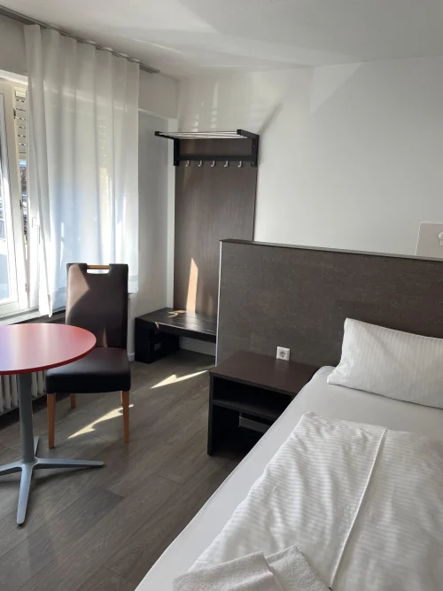Modernes Schlafzimmer mit großem Bett, Kleiderschrank und zwei Stühlen am Fenster. (KI generiert)