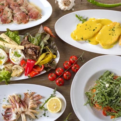 Verschiedene gesunde Gerichte: Salate, Avocado, Lachs, Ei und Brot auf Holztisch. (KI generiert)