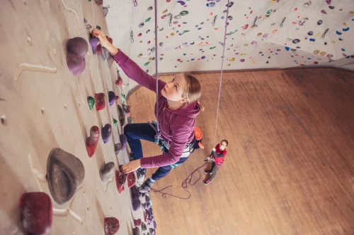 Kind auf Holztreppe mit Rollkoffer, hält Hand eines Erwachsenen. (KI generiert)