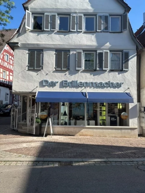 Fachgeschäft für Brillen mit Schnee bedecktem Dach und Schaufenster. (KI generiert)