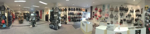 Ein breiter Blick auf ein Geschäft mit Handtaschen und Accessoires. Handtaschen hängen an Wänden und Ständern. (KI generiert)