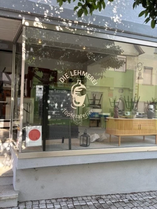 Schilder für Töpferatelier "Die Lehmerie" mit Keramikfigur und Holzfass. (KI generiert)