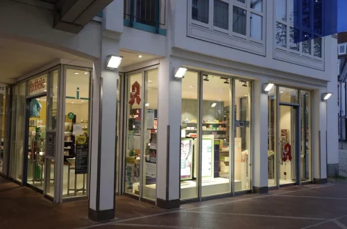 Leere Apotheke mit hohen Regalen, Schaufenstern und Verkaufstheke. (KI generiert)